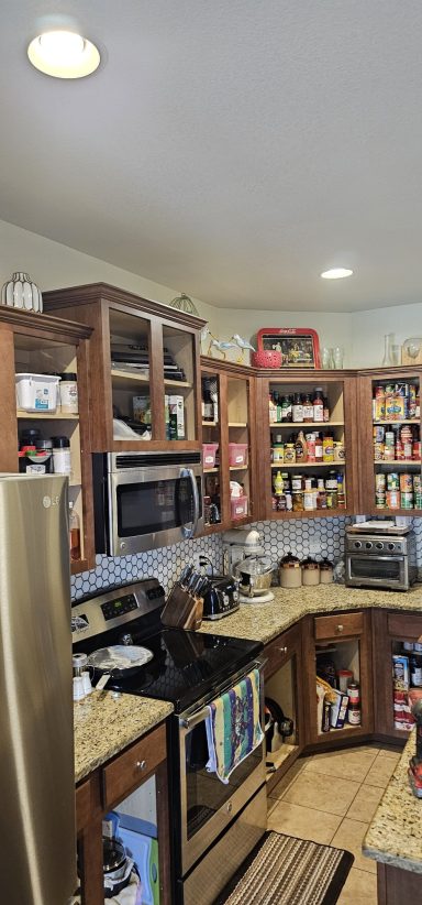Pre Kitchen remodel Cozy kitchen with wooden cabinets, stainless steel appliances, and various food items.