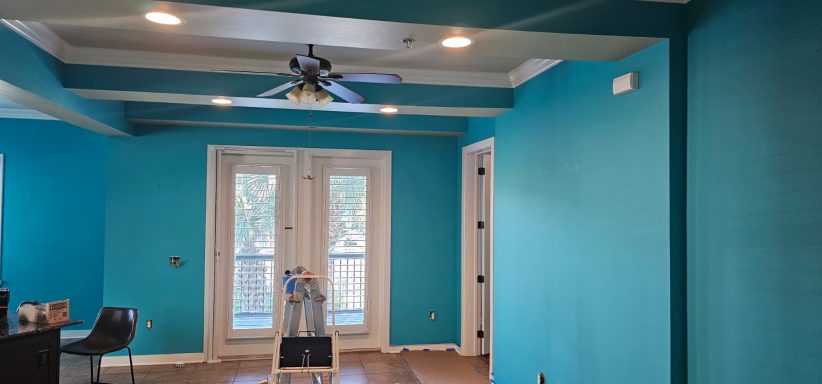 Before: Condo living room A bright turquoise room with a ceiling fan and double doors leading outside.